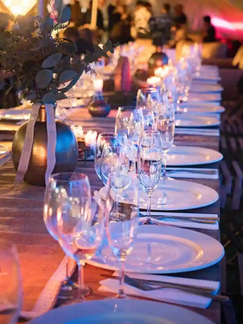Prostřený svatební stůl s talíři skleničkami a příbory
