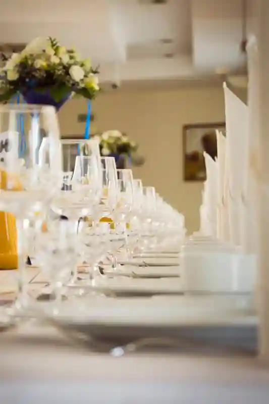 Řada sklenic na svatebním stole připravená pro mnoho hostů, jsou tam sklenice na víno i na sekt. 